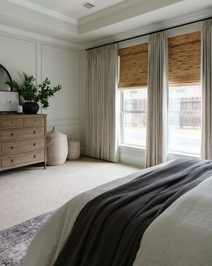 a bedroom with a bed, dresser and window covered in drapes on the windowsill