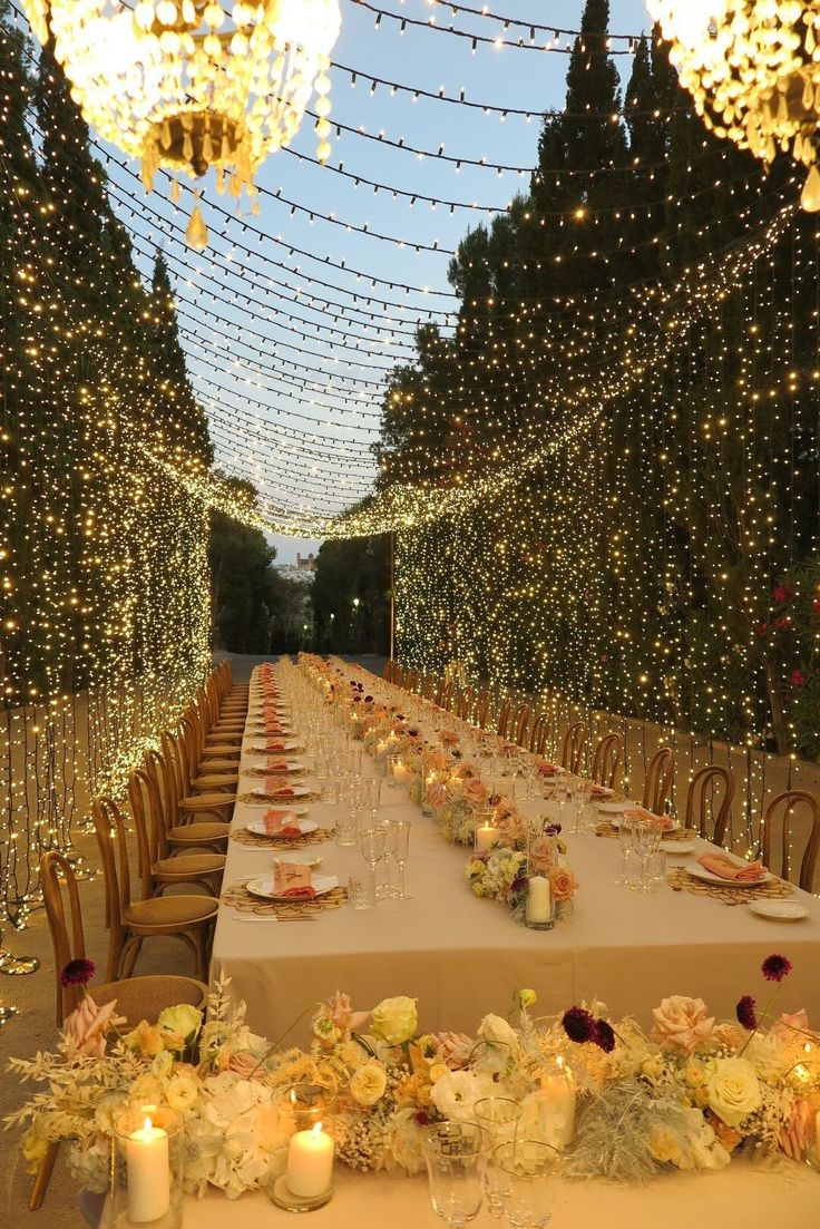 a long table is set up with candles and flowers for a formal dinner in an outdoor setting