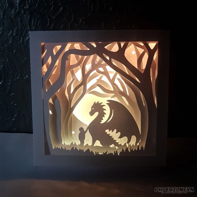 a card with an image of a dragon in the woods at night, cut out from paper