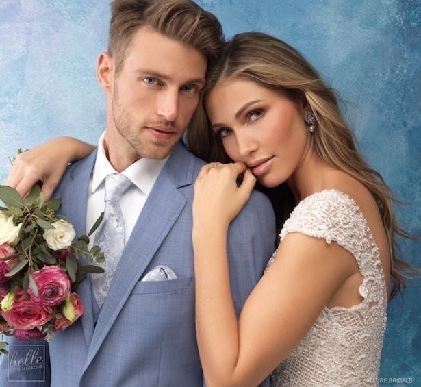 a man and woman are posing for a photo with their arms around each other as they hold flowers