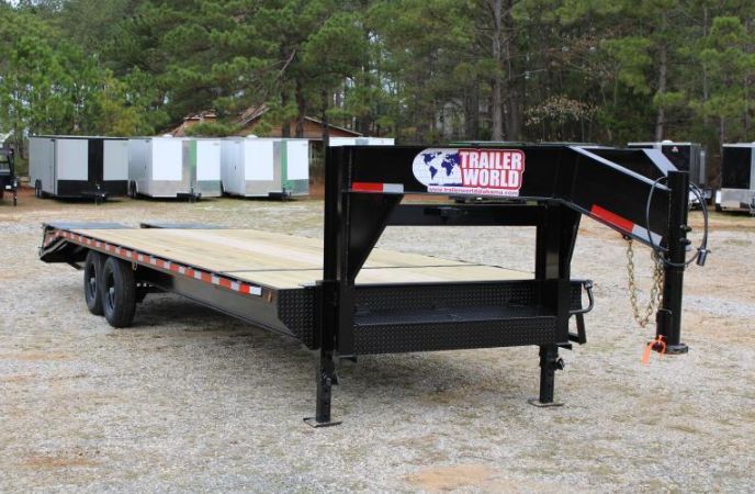 a flatbed trailer is parked in a lot with other trailers and trees behind it