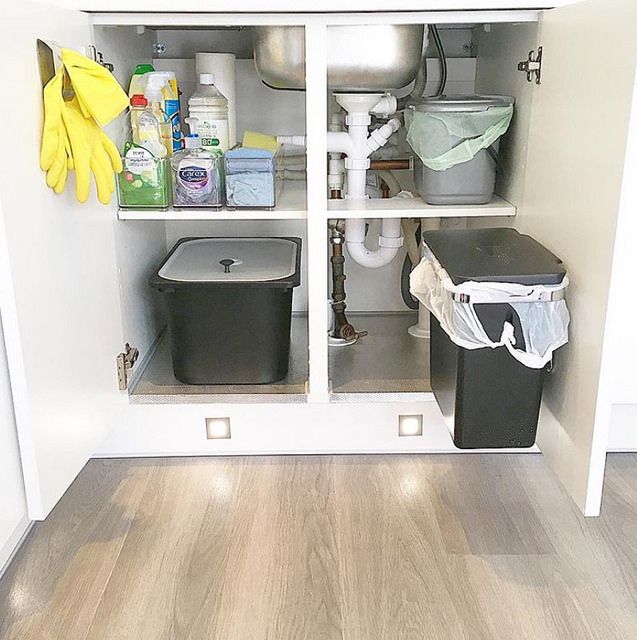 an open cabinet filled with cleaning supplies and other household items on top of wooden floors