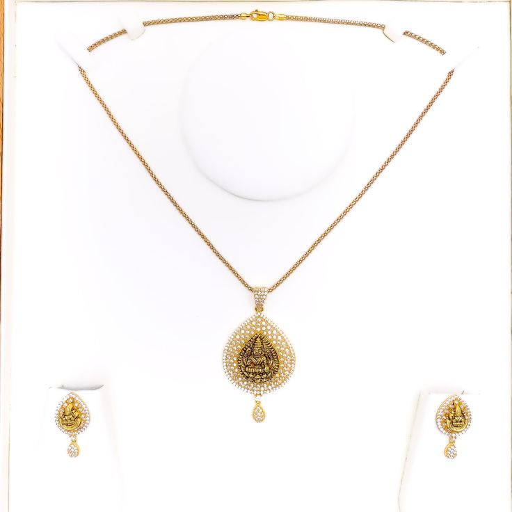 Embrace luxury with our Impressive Lakshmi 22k Gold CZ Pendant Set. Crafted from 14.5g of pure 22k gold, adorned with dazzling Cubic Zirconia. The pendant boasts a 2.2" length, complemented by matching 1" earrings with secure screw backs. Elevate your style with this exquisite 3-piece set. PRODUCT DETAILS Gold Purity(karat): 22k Item Weight(grams): 14.5 Item Finish: Yellow Gold Stone: Cubic Zirconia Pendant Length: 2.2" Matching Earrings: Included Earring Length: 1" Earring Post: Screw Back Numb Elegant 22k Gold Jewelry Sets For Puja, Gold Bollywood Necklace With American Diamond, Bollywood Style Gold Necklace With American Diamonds, Gold American Diamond Jewelry Sets For Diwali, Traditional Jewelry Sets With Diamond Accents, Diwali Gold Jewelry Sets With American Diamonds, Gold American Diamond Temple Jewelry Sets, Gold Necklaces With Intricate Designs In Cubic Zirconia, Festive Gold Jewelry Sets With Cubic Zirconia