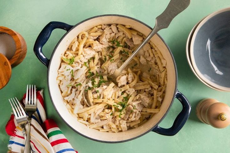 a large pot filled with food next to two bowls and spoons on top of a table