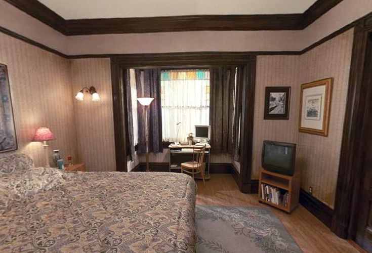 a bedroom with wood paneling and carpeted flooring, along with a television