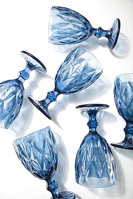 four blue glass vases sitting next to each other on top of a white surface