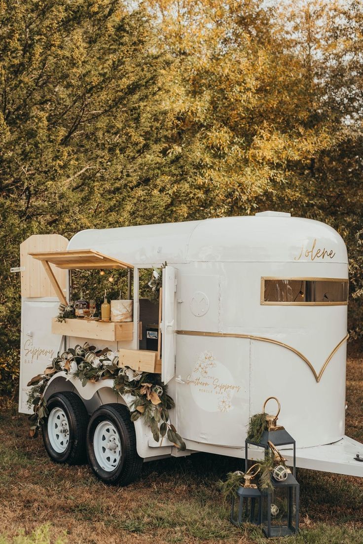 an old fashioned trailer is decorated with greenery