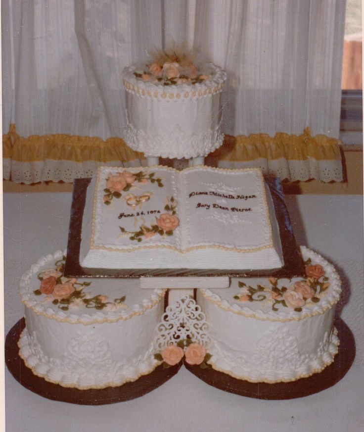 three tiered wedding cakes with flowers on each layer and an open bible in the middle