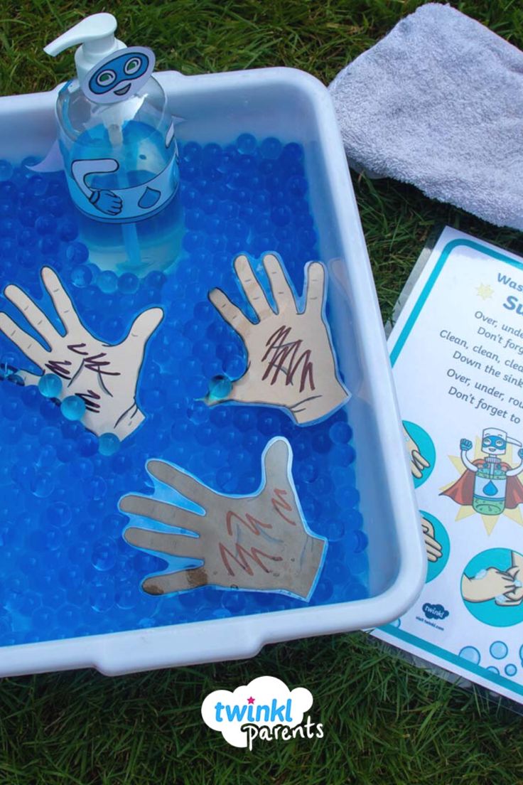 two hands are in a bathtub with water and soap on the ground next to it