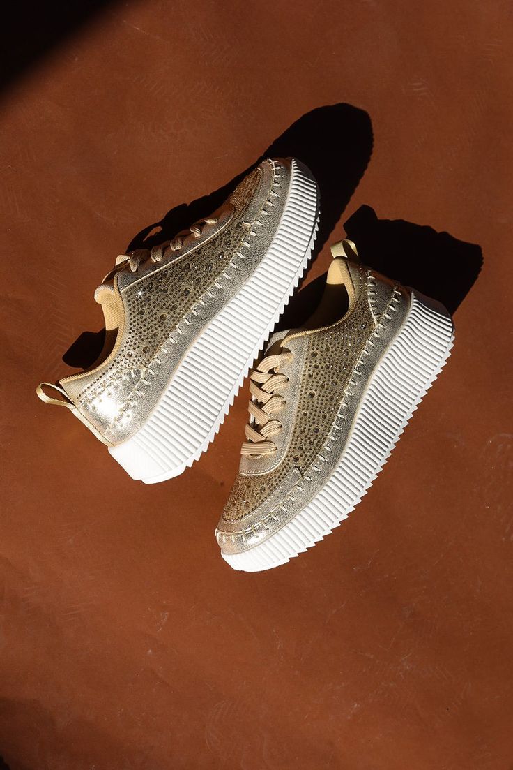 Step into the spotlight with our Golden Hour Bedazzled Sneakers. Featuring a platform design and a bedazzled gold exterior, these sneakers are both comfy and fashion-forward. Perfect for adding some sparkle to your everyday style! Bedazzled platform sneakers Gold Fits true to size Perfect for everyday wear Metallic Sneakers With Perforations And Round Toe, Metallic Sneakers With Perforations, Sporty Gold Sneakers With Perforations, Gold Low-top Sneakers With Textured Sole, Gold Low-top Sporty Platform Sneakers, Gold Low-top Platform Sneakers, Gold High-top Sneakers With Perforated Toe Box, Metallic Sneakers With Perforated Toe Box, Gold Synthetic Sneakers For Streetwear