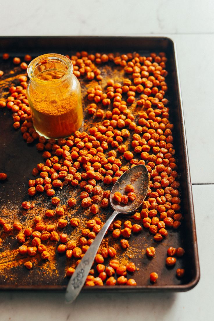 a tray with some food on it and a spoon sitting next to the bowl full of chickpeas