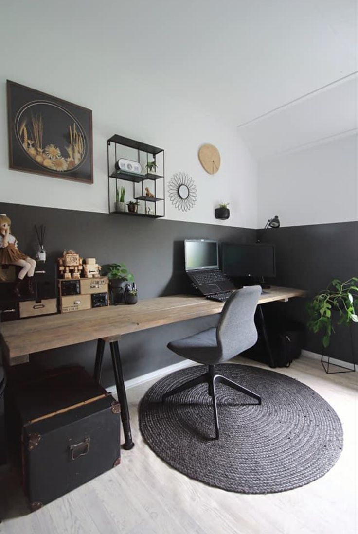 a room with a desk, chair and pictures on the wall above it in black and white