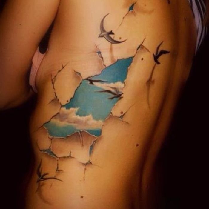 a woman's stomach with birds flying over the water and clouds on her side