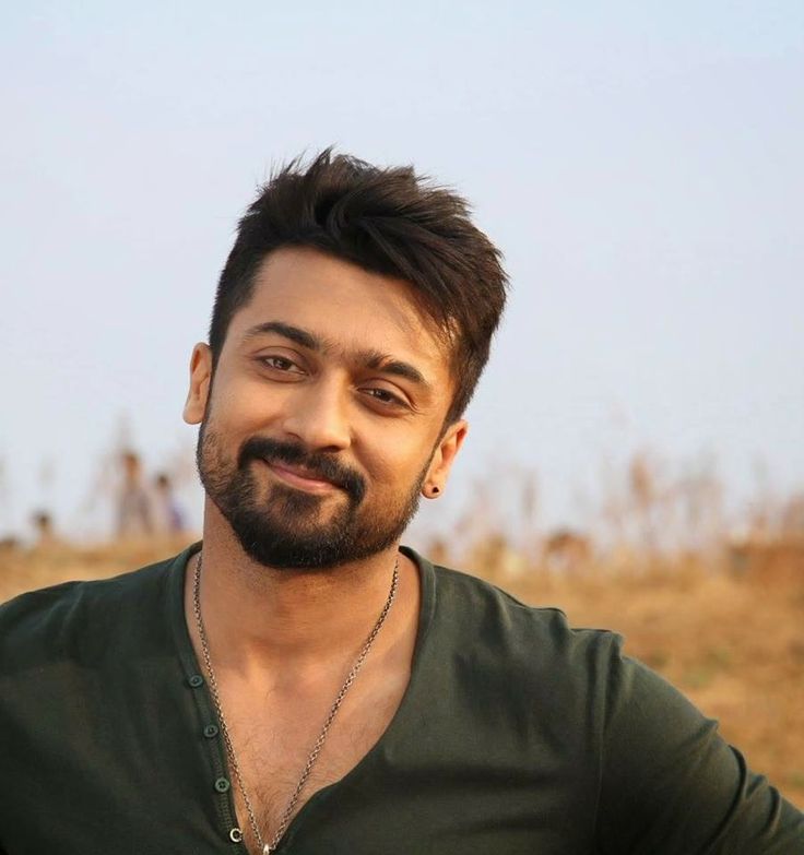 a man with a beard and green shirt standing in front of a brown grassy field