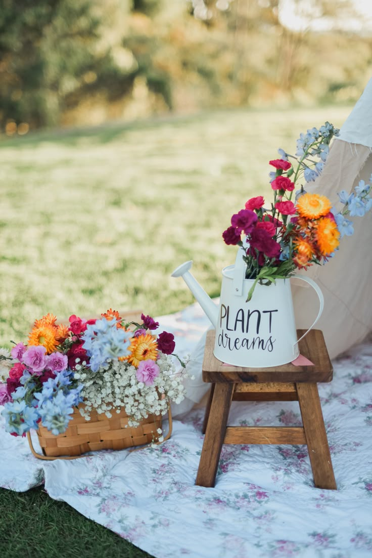 two flower pots sitting on top of a blanket next to a wooden stand with flowers in it