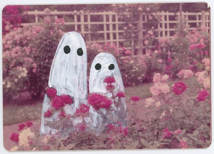 two ghost statues standing in the middle of flowers