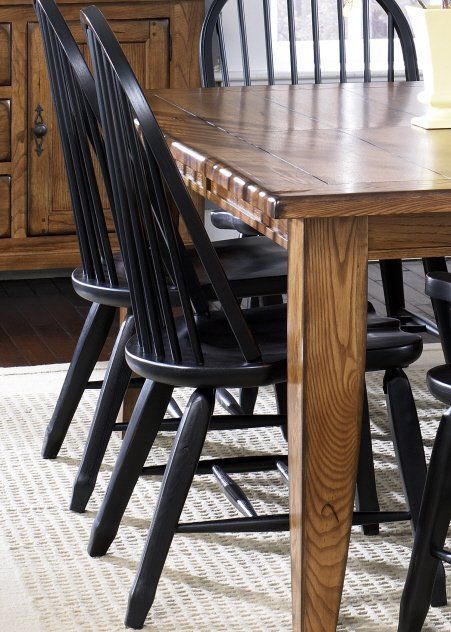 a wooden table with black chairs and a white rug on the floor in front of it