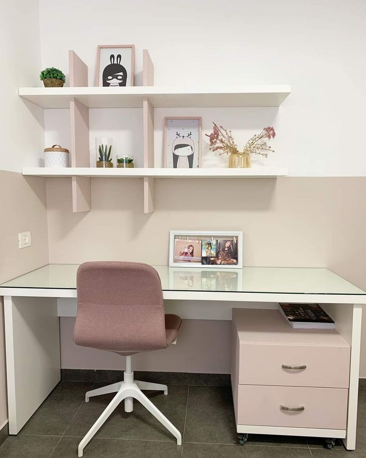 a white desk with a pink chair in front of it and shelves on the wall