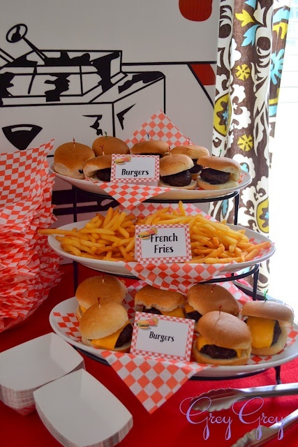 sandwiches and french fries are displayed on three tiered trays with red checkered paper