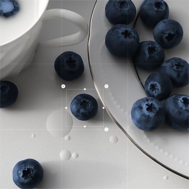 some blueberries are on a white plate and next to a bowl of blueberries