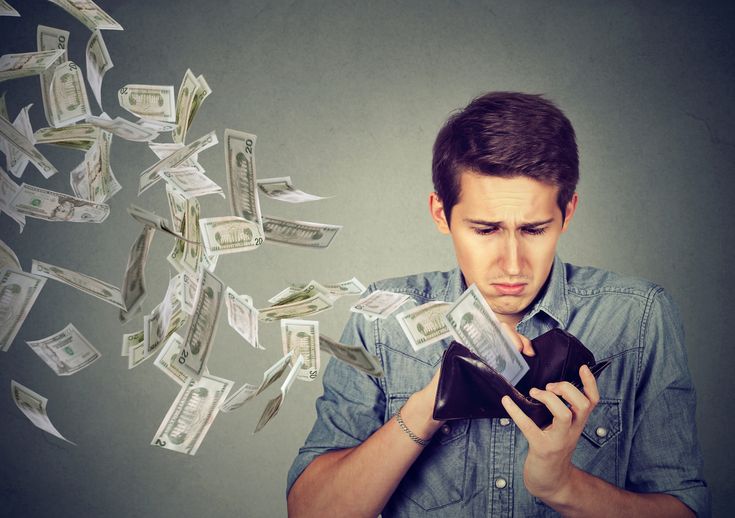 a man is looking at money falling out of his purse and he is holding a cell phone