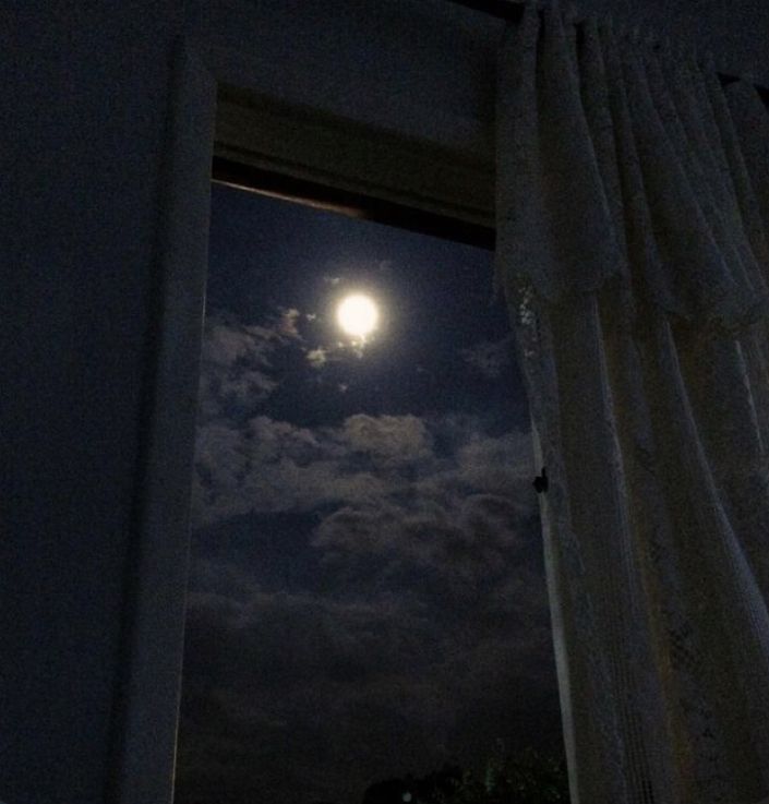 the full moon is seen through an open window