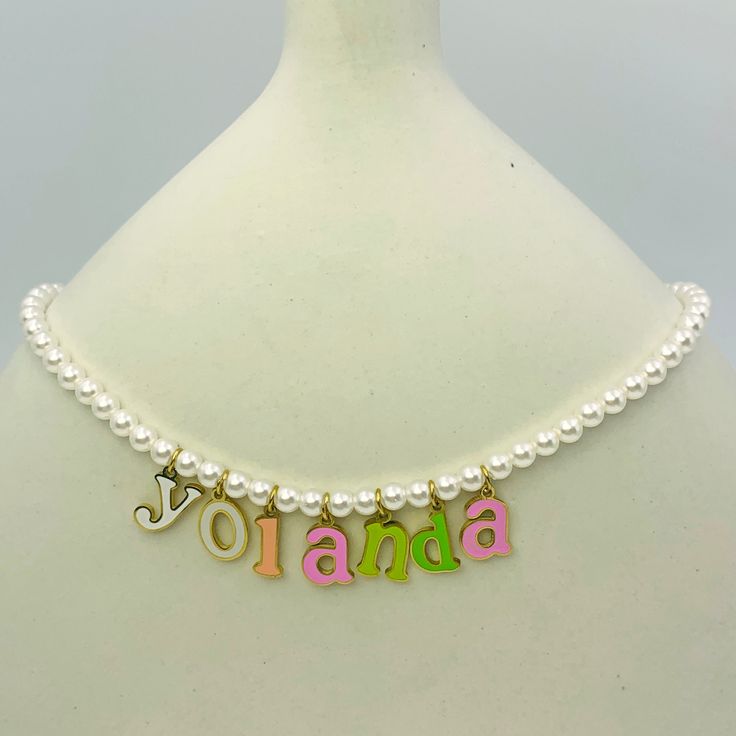 Embrace elegance with a touch of fun with our Charmed Pearl Letter Necklace. This exquisite piece features a string of lustrous pearls, accentuated by colorful enamel-coated letters that spell out your chosen name or meaningful word. Perfect for adding a personalized charm to any outfit, this necklace is both sophisticated and playful, making it a standout accessory in your jewelry collection. Trendy White Pearl Charm Necklace, Letter Beads Name Necklace For Personalized Gifts, Personalized White Pearl Charm Necklaces, Personalized White Pearl Charm Necklace, Customizable White Name Necklace, Trendy White Custom Name Jewelry, Custom Name Initial Pendant Necklace In White, White Custom Name Charm Necklace For Personalized Gift, Customizable White Initial Pendant Name Necklace