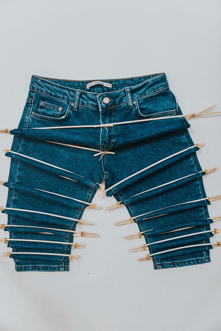 a pair of blue jeans with pins stuck in them on a white background, the bottom part of the pants is lined up