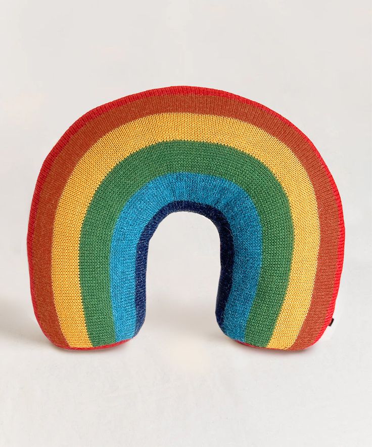 a knitted rainbow shaped pillow on a white surface with the end cut out to show it's colors