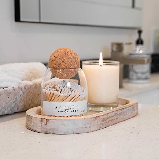 a candle sitting on top of a counter next to a glass jar filled with matches