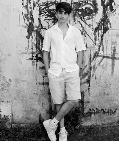 a young man standing in front of a wall with graffitti on the side