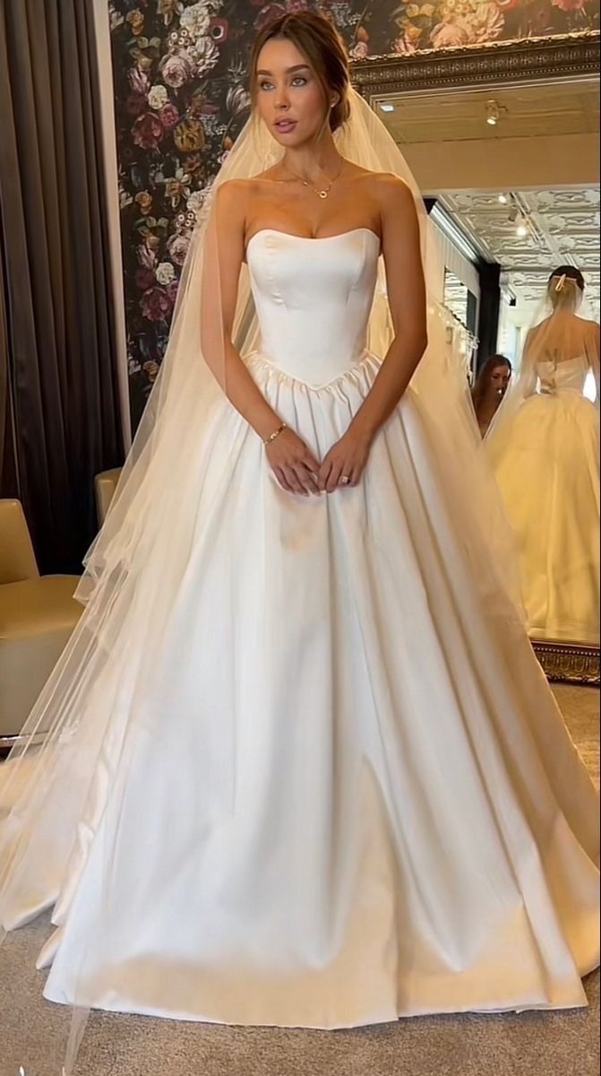 a woman in a white wedding dress standing next to a mannequin