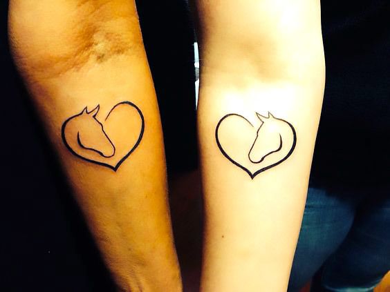 two people with matching tattoos on their arms, one has a horse and the other has a heart