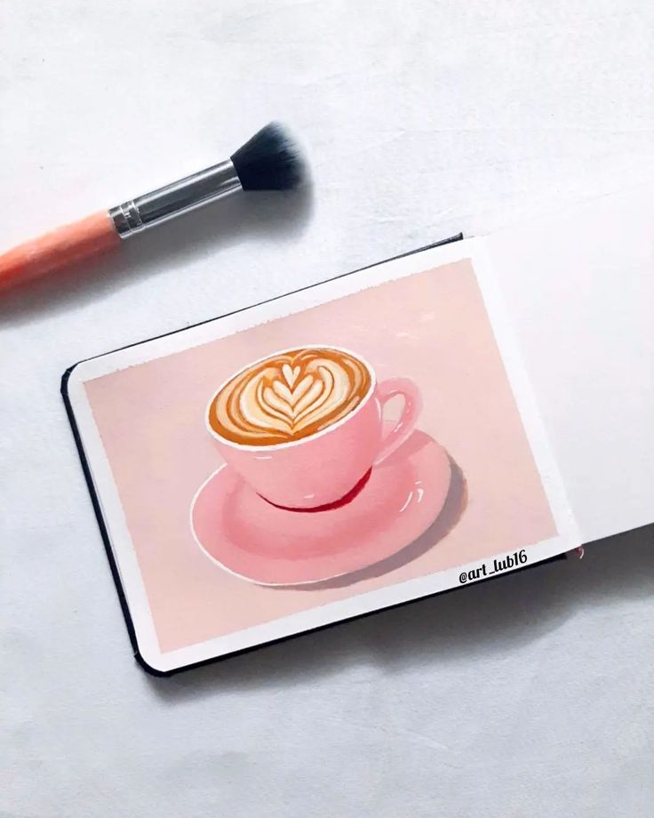 a cup of coffee on top of a pink plate next to a brush and eye shadow