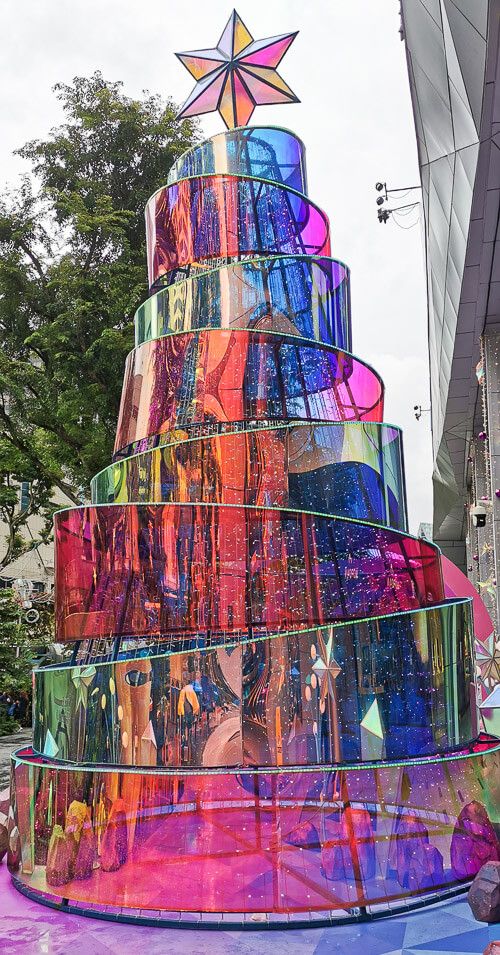 a colorfully decorated christmas tree in the middle of a street