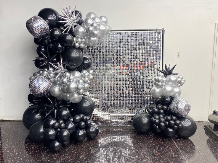 black and silver balloons are arranged in the shape of an arch on a granite countertop