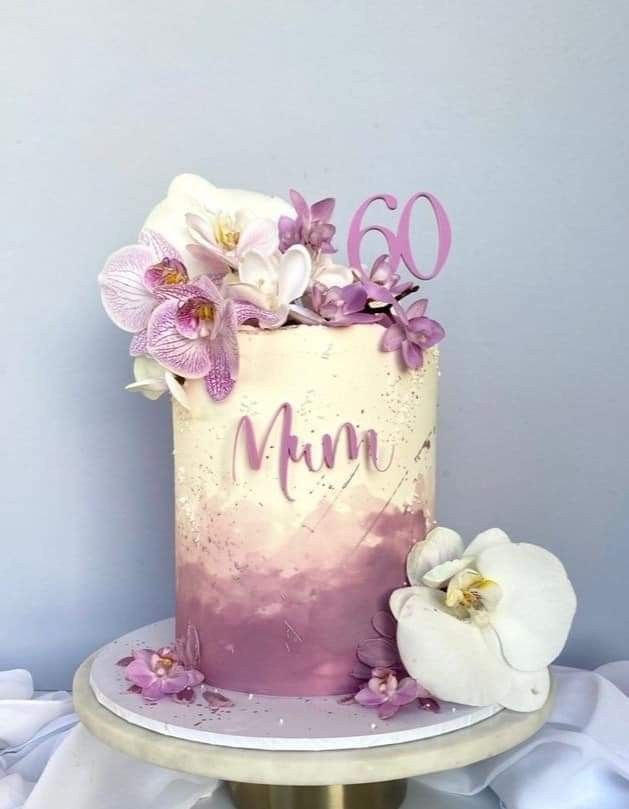 a pink and white cake with flowers on the top is sitting on a gold pedestal