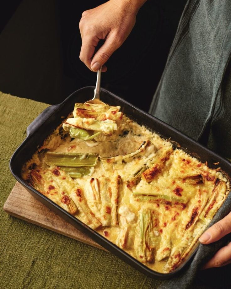 a person cutting into a casserole dish with a knife and fork in it