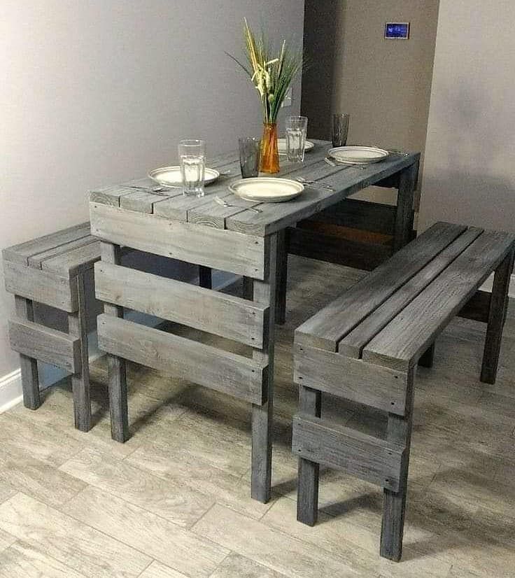 a wooden table with benches and plates on it in front of a vase filled with flowers