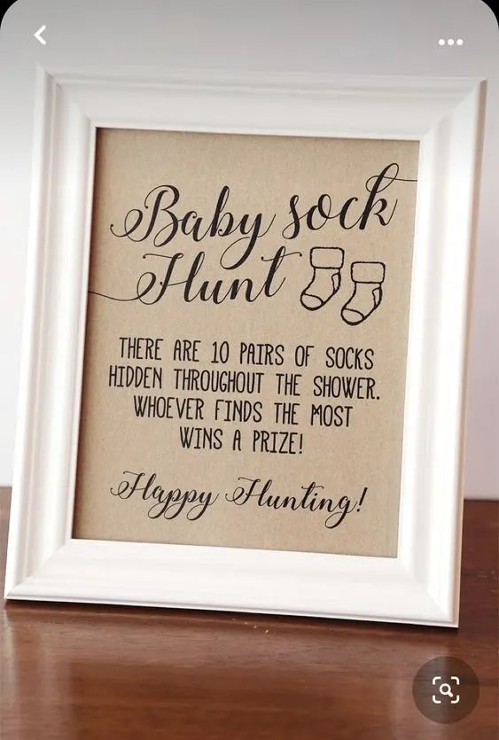 a baby sock hunt is displayed in a white frame on a wooden table with the words,