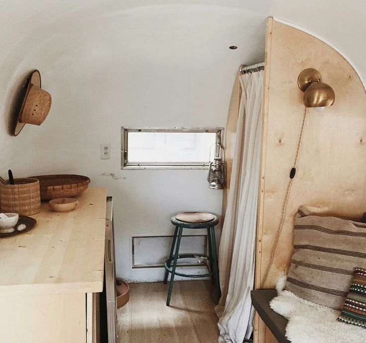 the interior of a tiny home with wood flooring and white walls, along with wooden furniture