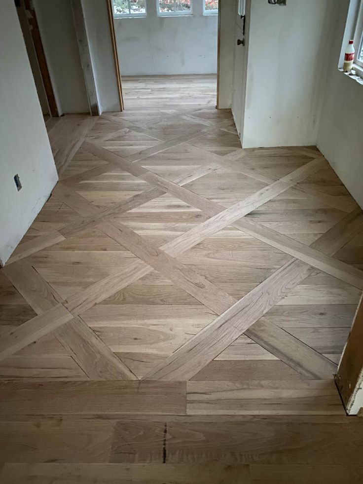 an empty room with wood flooring and white walls, looking into the hallway from another room