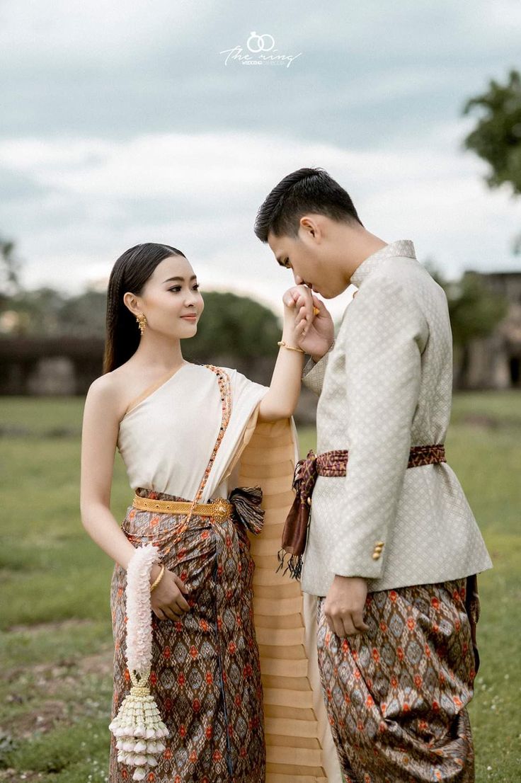 a man and woman standing next to each other in front of a grass covered field