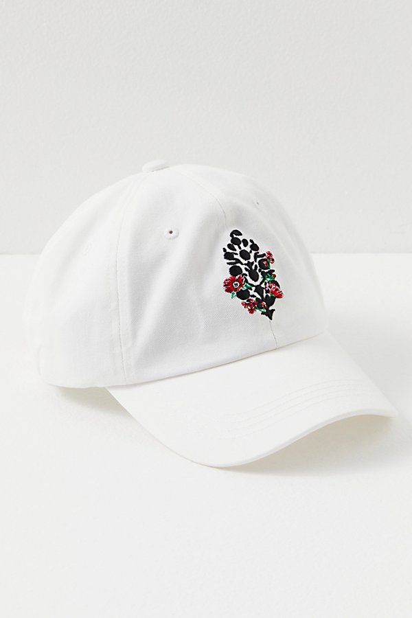 a white baseball cap with floral embroidered on the front and back side, sitting on a white surface