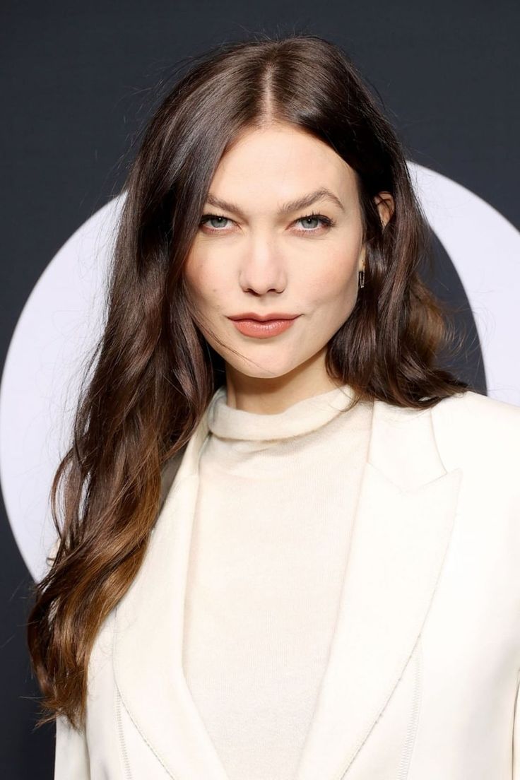 a woman with long hair wearing a white suit