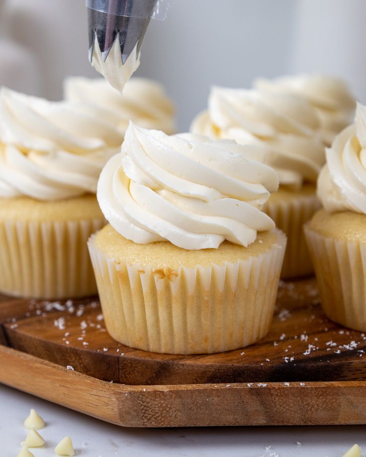 cupcakes with white frosting being piped into the icing on top