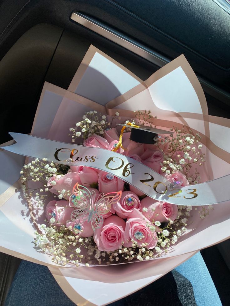 a bouquet of pink roses and baby's breath sits in the front seat of a car