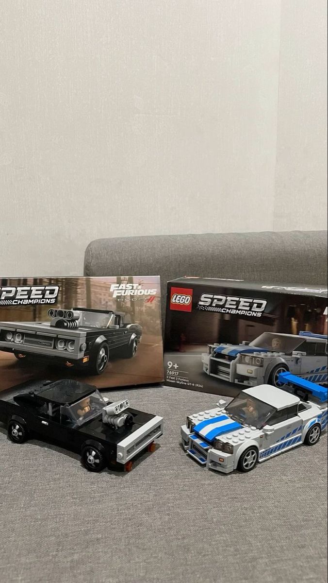 three toy cars are on the floor next to a box with legos in it