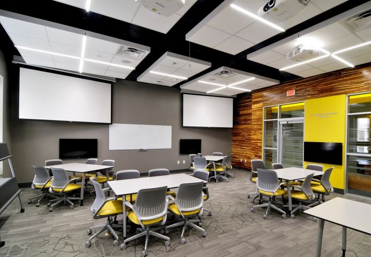 an empty classroom with desks and chairs in front of whiteboards on the wall