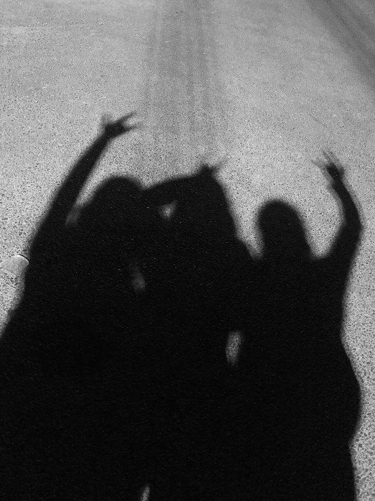 two people standing in the middle of an empty road with their arms up and hands raised